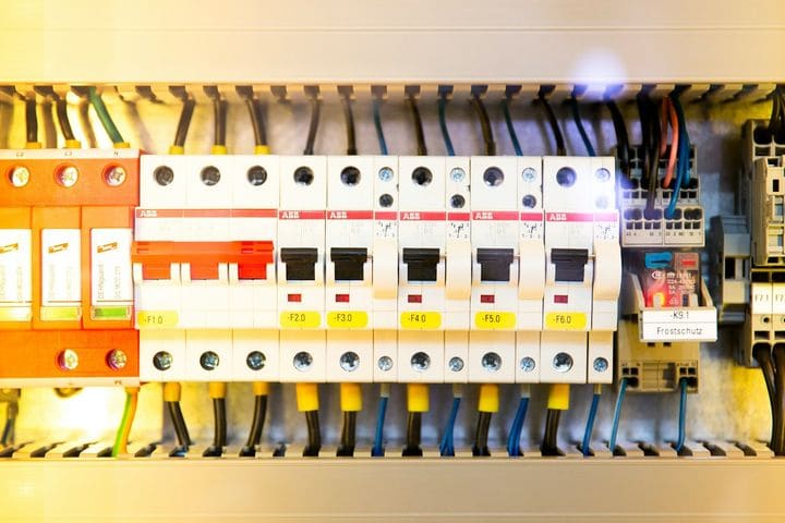 Rows of circuit breakers and colour-coded wiring inside an open electrical switchboard