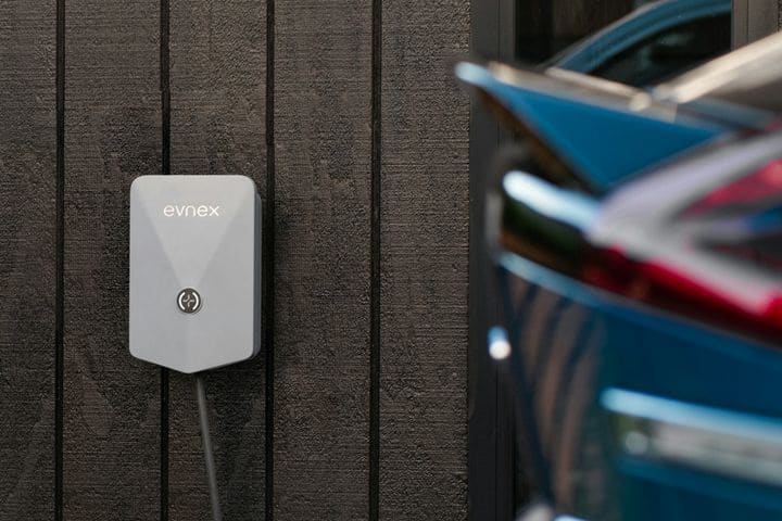 Silver Evnex E2 charger on a black timber wall with an electric car parked beside it