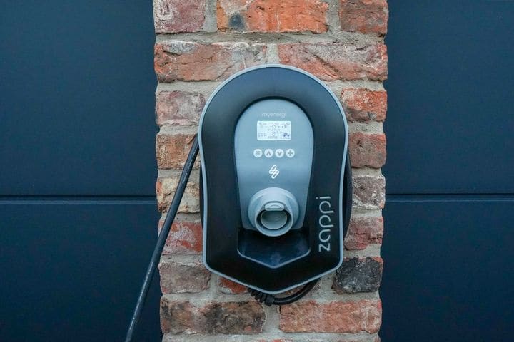Black myenergi zappi charger with a display screen, mounted on a brick pillar